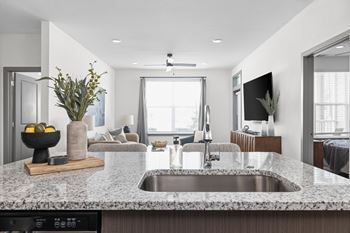 A modern kitchen with a granite countertop and a stainless steel sink.